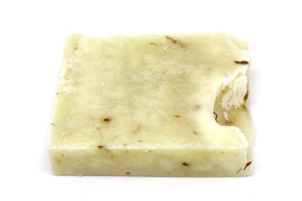 A creamy coloured soap, with black dots, on a white background.