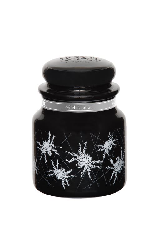 A black candle, with a grey label with pictures of Spiders on the label, on a white background.
