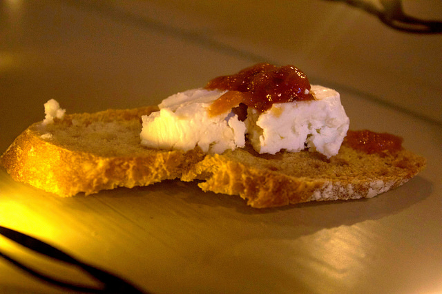 A lightly toasted piece of Bread, with some Sun-Dried Tomatoes, and Goats Cheese, on a tan background.