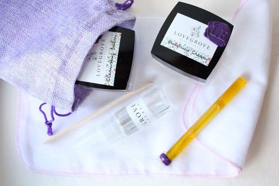 Two black boxes with white labels saying cleansing balm and moisture cream written on them, on a white table, on a white background.