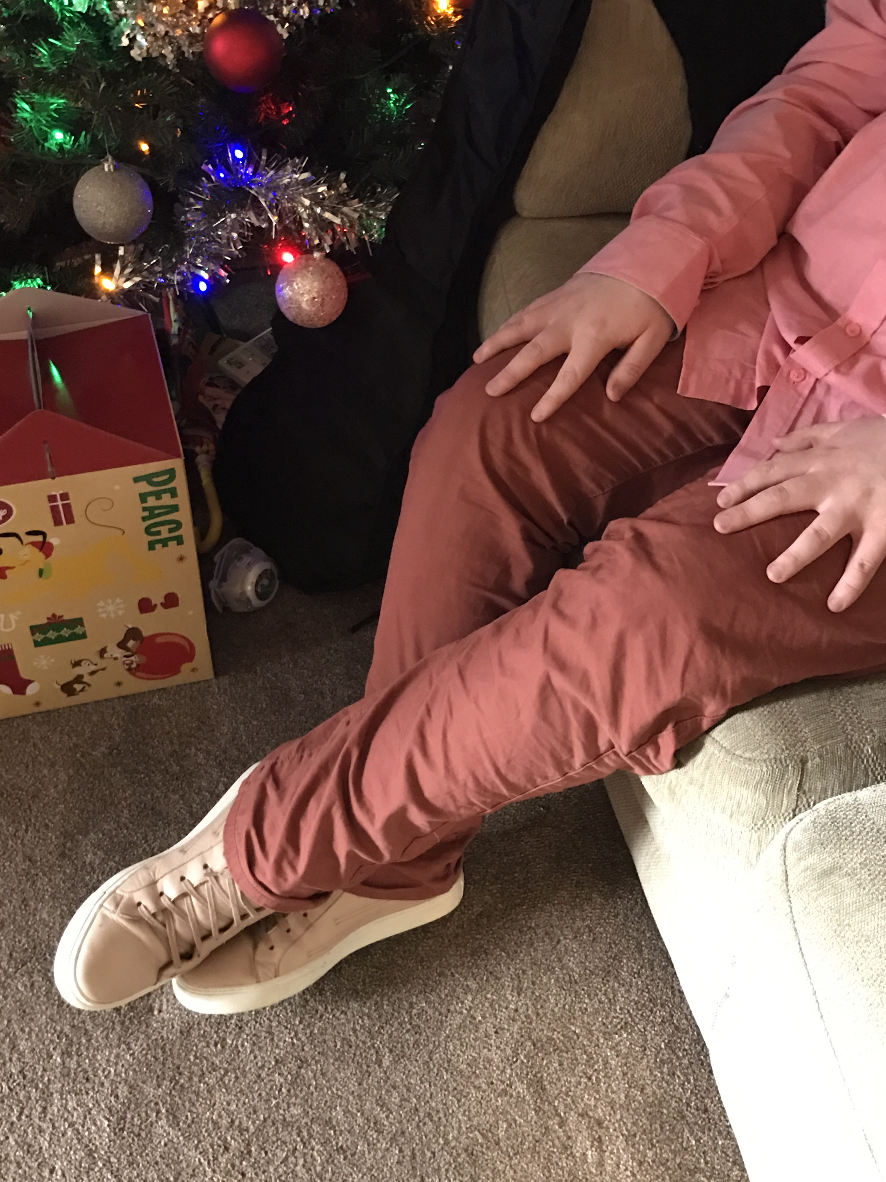 Some long burgundy chinos with some pale pink boots with white laces, on a twinkly blue and grey background.