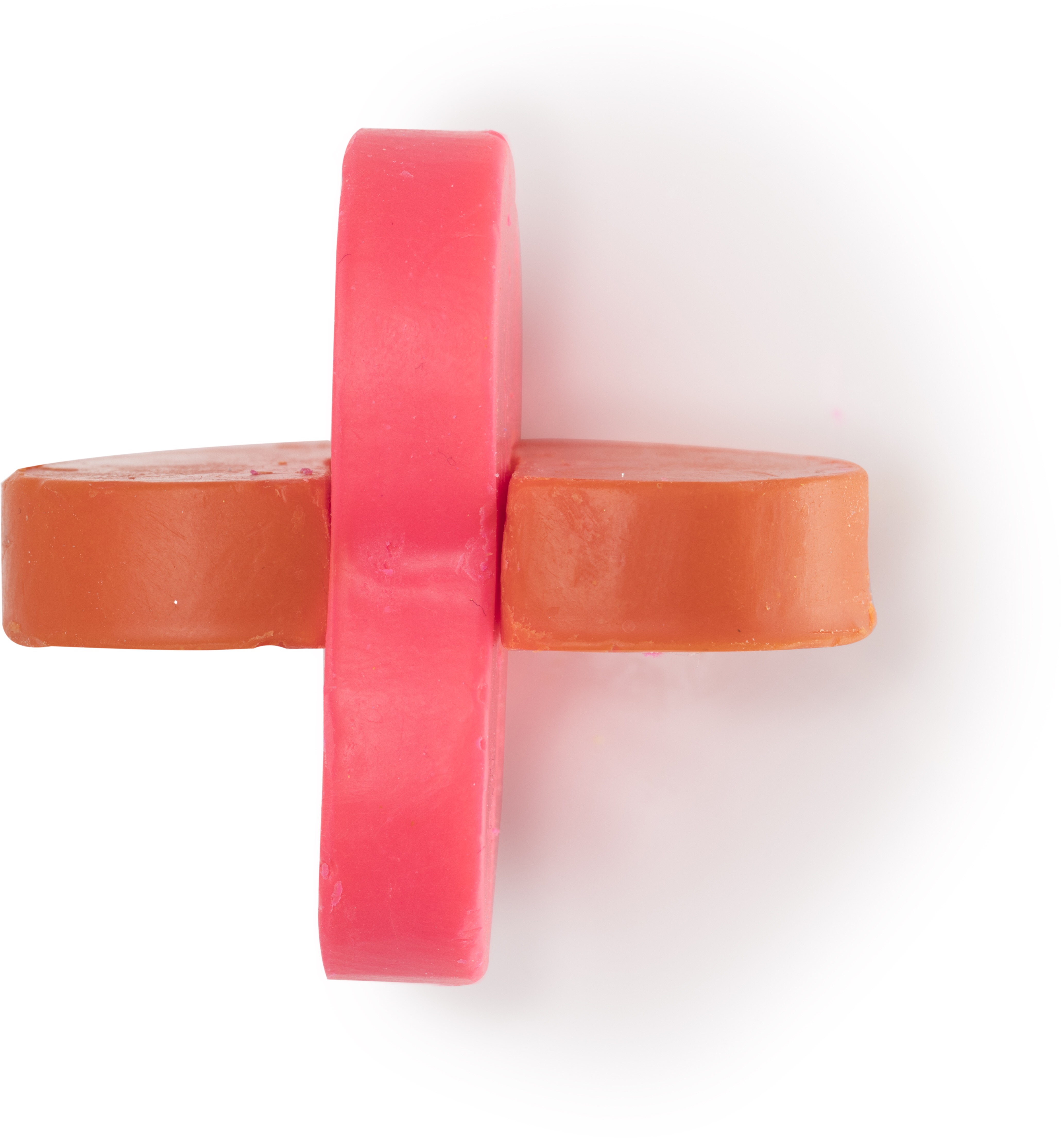 A block of pink solid oils in a plus shape that represents the cross section of the two hearts beating as one bath oil, on a white background.