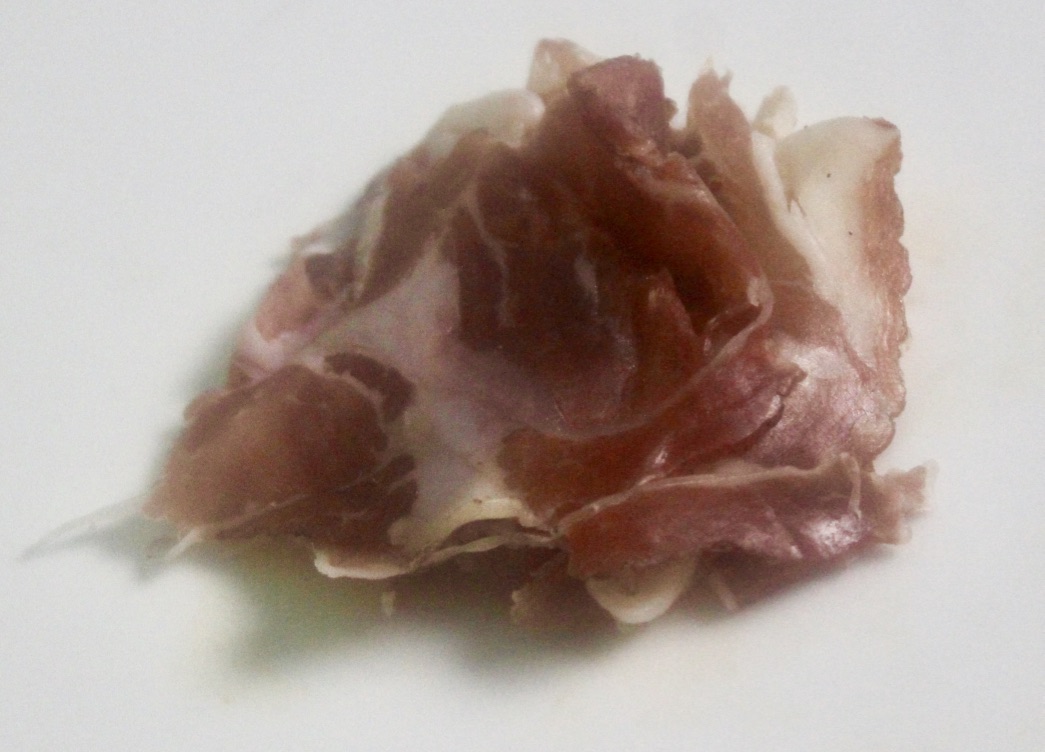 Some wavy pieces of brown meat piled together on a white background.