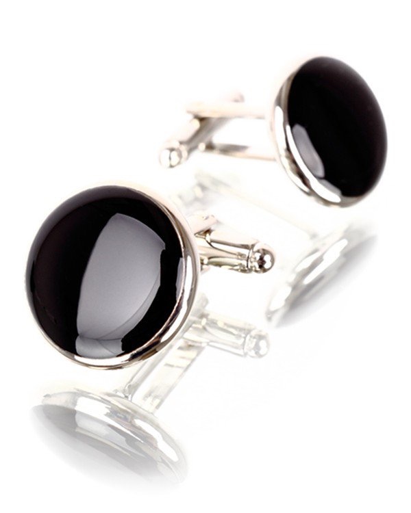 Two big black onyx circular cufflinks with metal ends that tie into the cuffs, on a white background