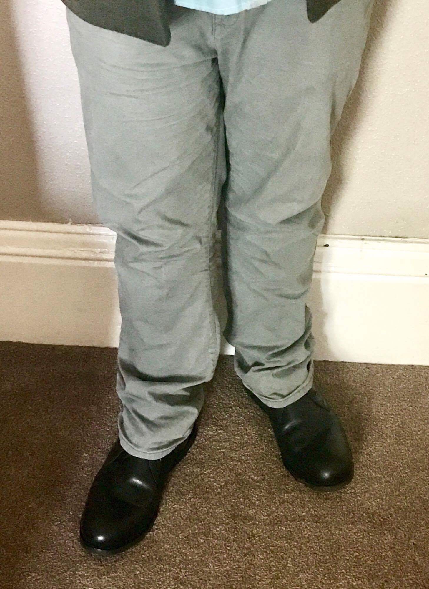 Me wearing a pair of light green chinos and a pair of black leather boots, on a light background.