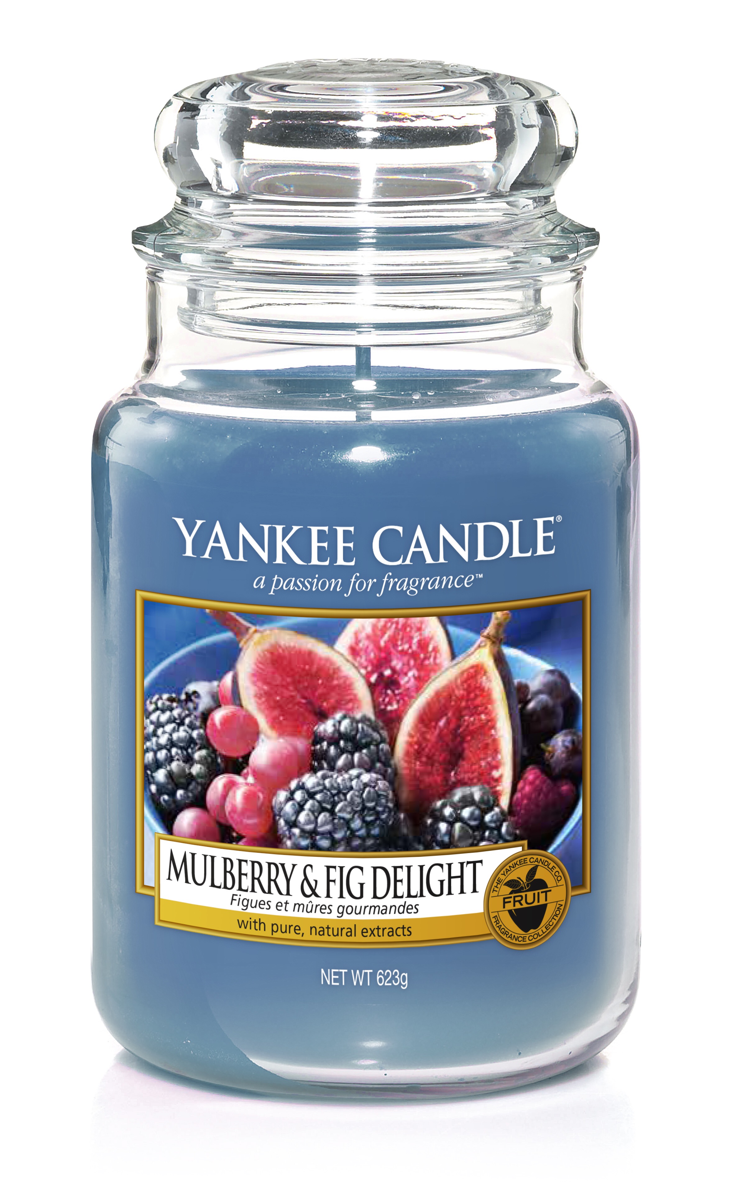 A tall glass jar full of some light sea blue coloured wax with a label that has yankee candle written in white writing, Mulberry & Fig Delight written in black writing, and a picture of some halved Figs and some mulberries on it, on a white background.