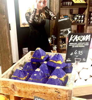 Some Purple triangular bubble bars with gold and silver tops in a square light wooden box, on a light background.