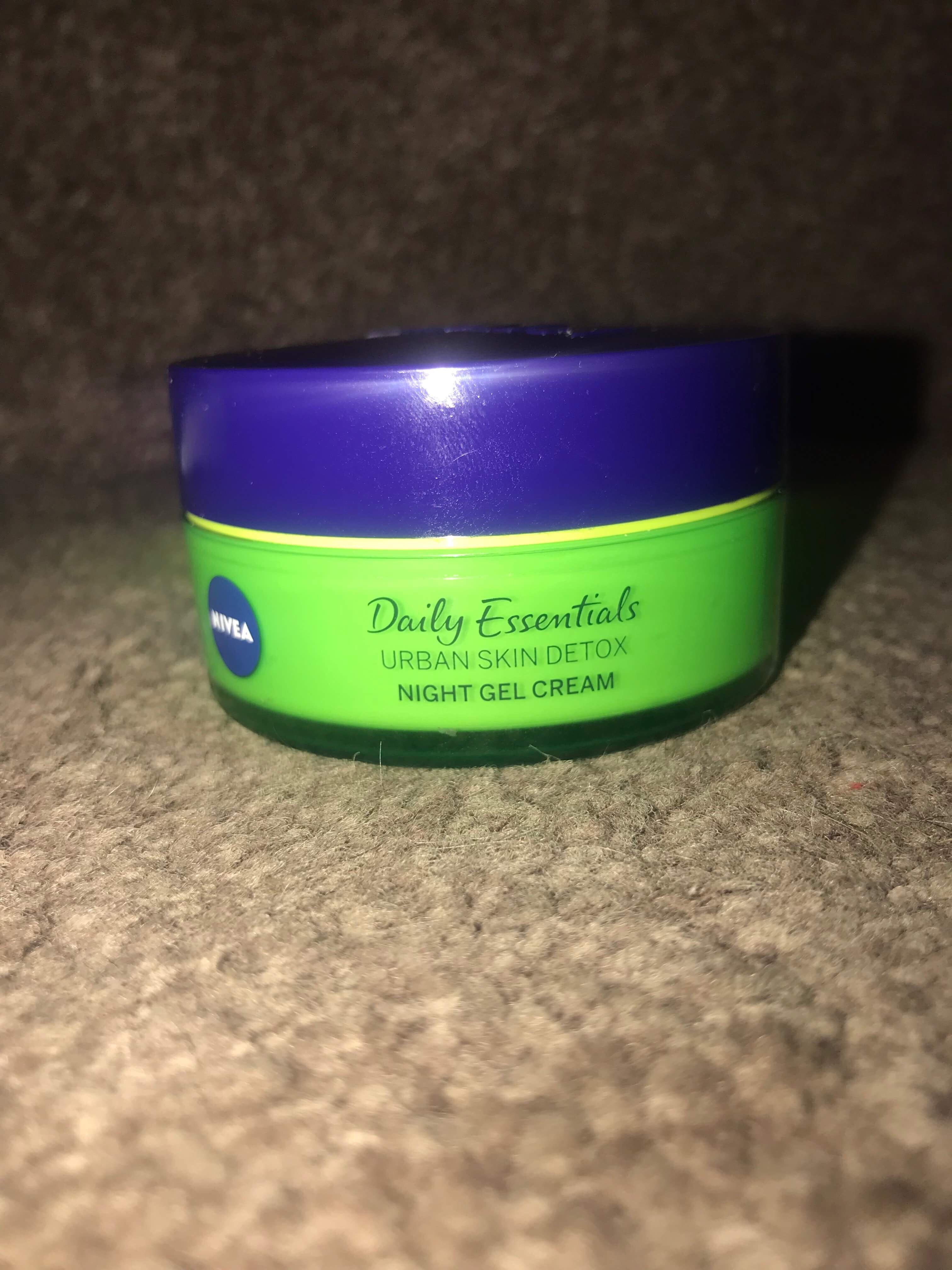 A short cylindrical deep Green plastic tub with a deep blue lid that has Nivea Urban Skin Defence Night Cream written in blue writing on it, on a white background.