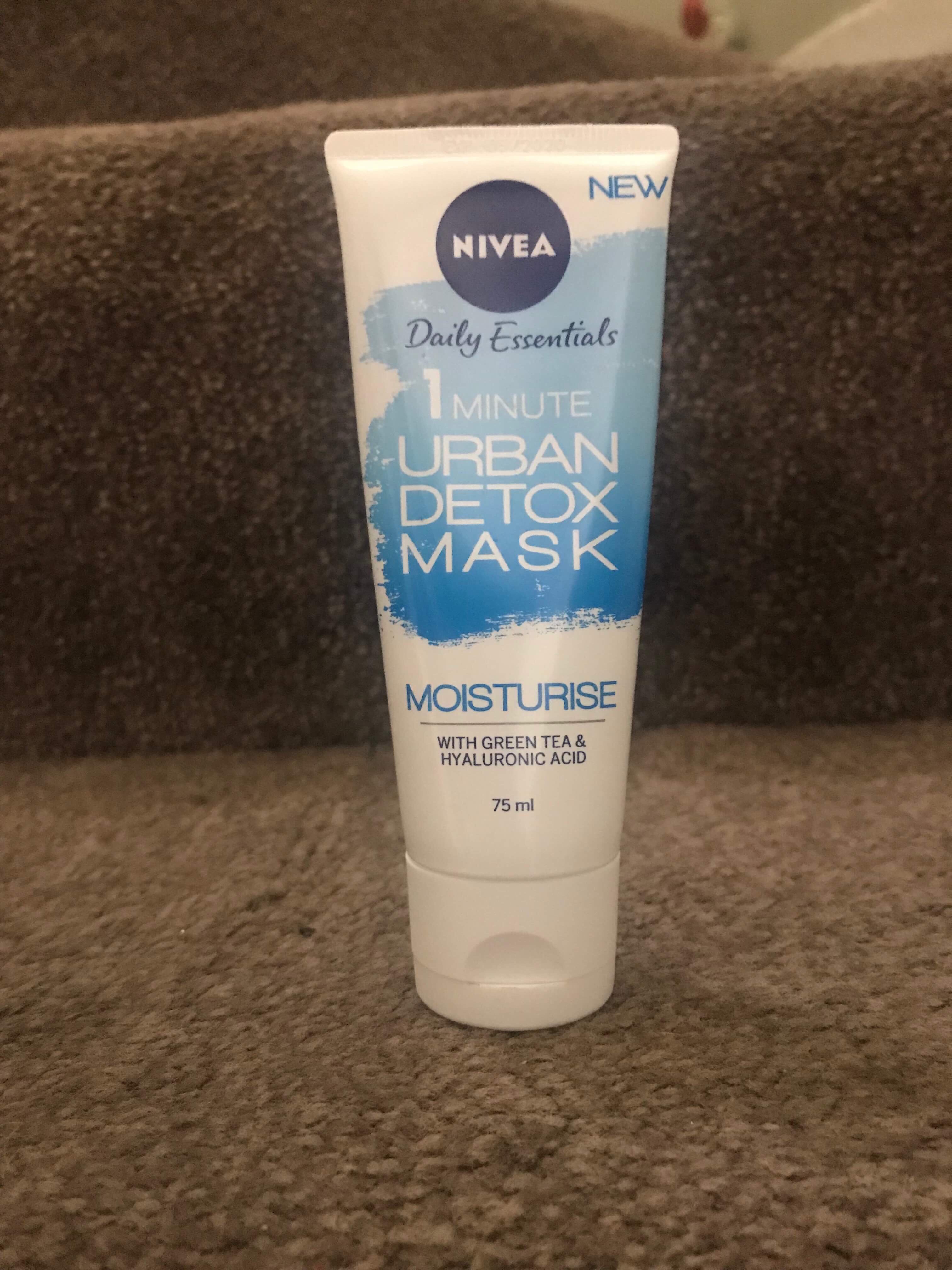 A tall thin white plastic tube that has Nivea Urban Skin Defence 1 Minute Detox Moisture Mask written in light blue writing on it, on a white background.