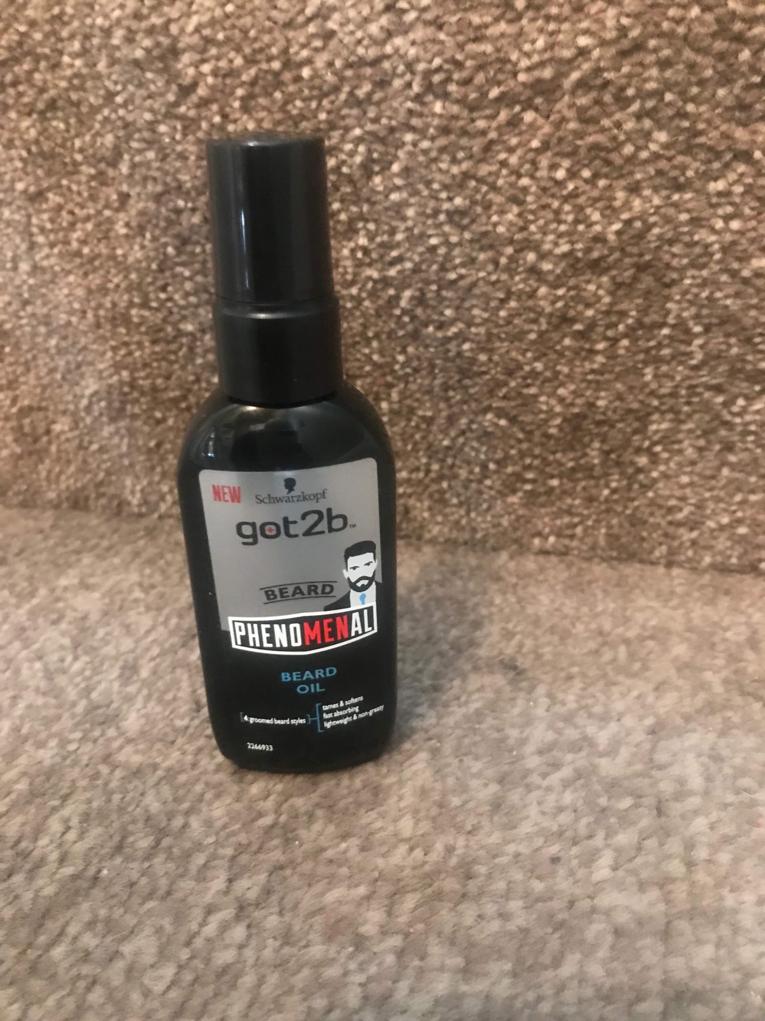 A tall rectangular black plastic bottle with a silver label that has Schwarzkopf Got2B Phenomenal Beard Oil written in bold black writing on it, on a white background.