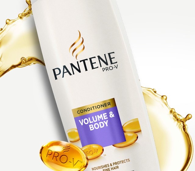 A tall rounded rectangular white plastic bottle with a white lid and a purple label that has Pantene Pro-V Volume & Body Conditioner written in bold white writing on it, on a white background.