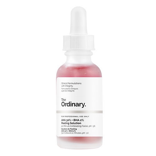 A short cylindrical clear glass bottle with a white pipette lid full of some dark red liquid and a white label that has The Ordinary written in bold black writing and 30% AHA + 2% BHA Peeling Solution written in smaller bold black writing on it, on a white background.