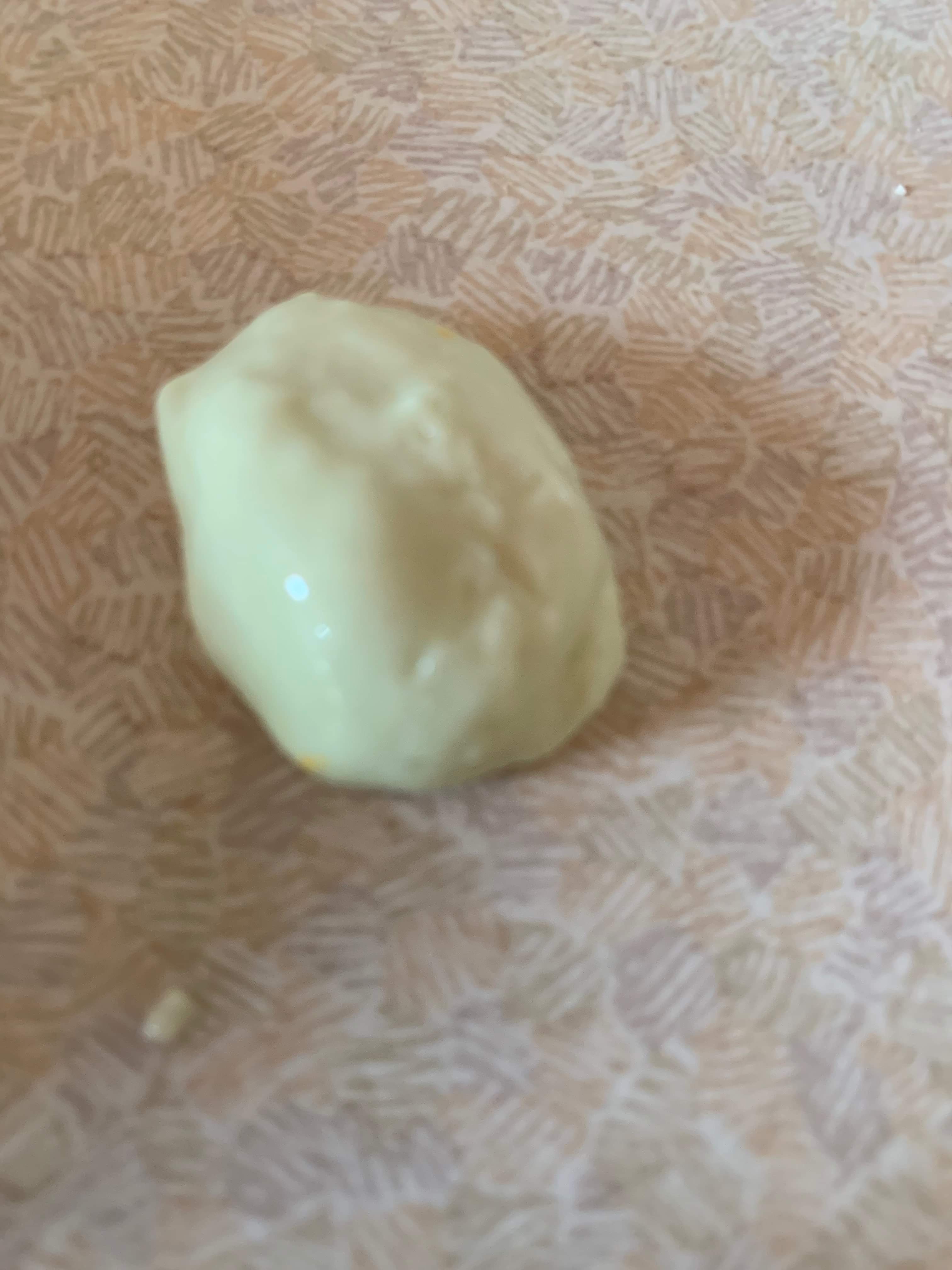 A large circular blob of milky yellow plasticine, on a white background.