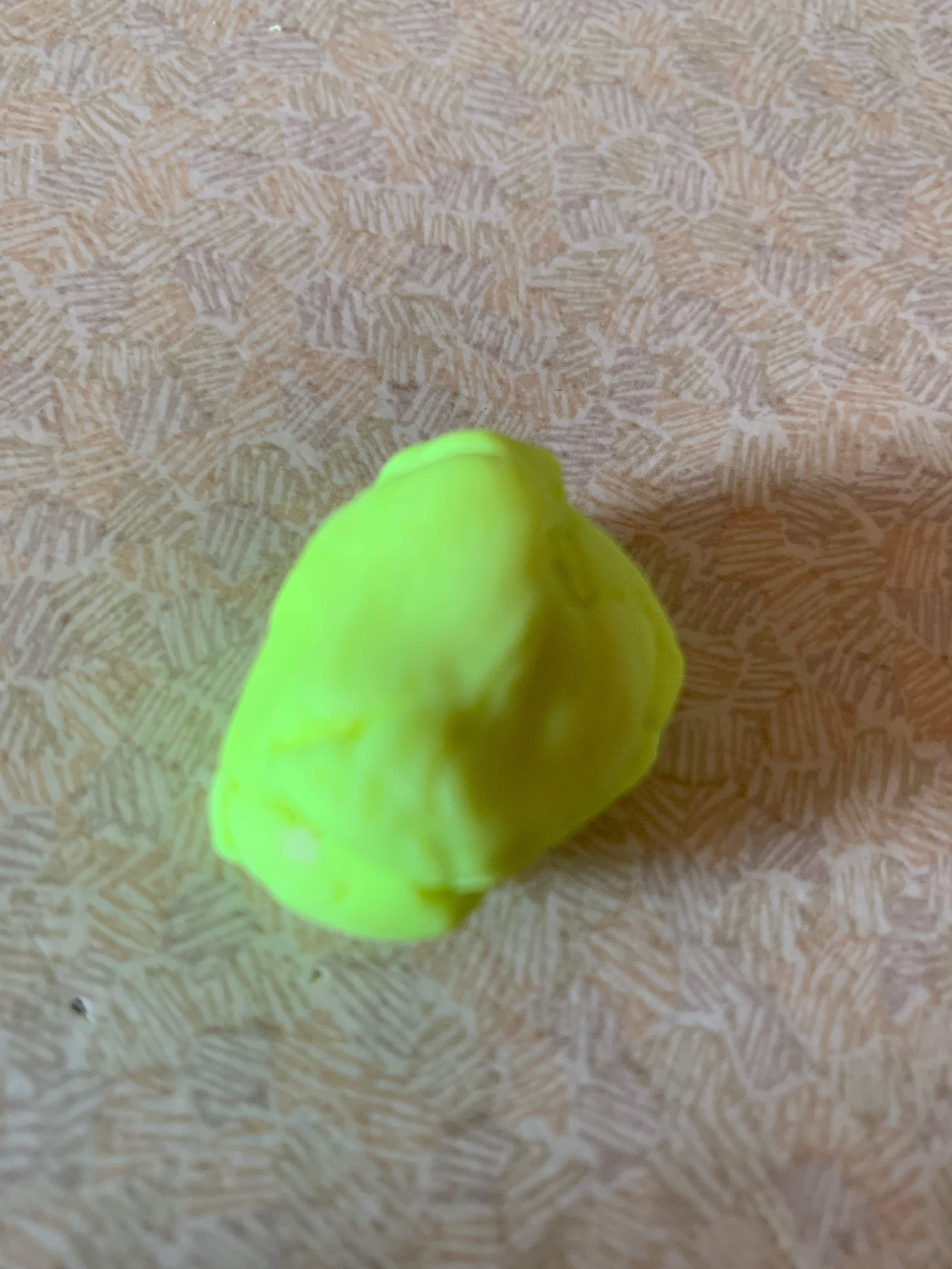 A large circular blob of bright yellow plasticine, on a white background.
