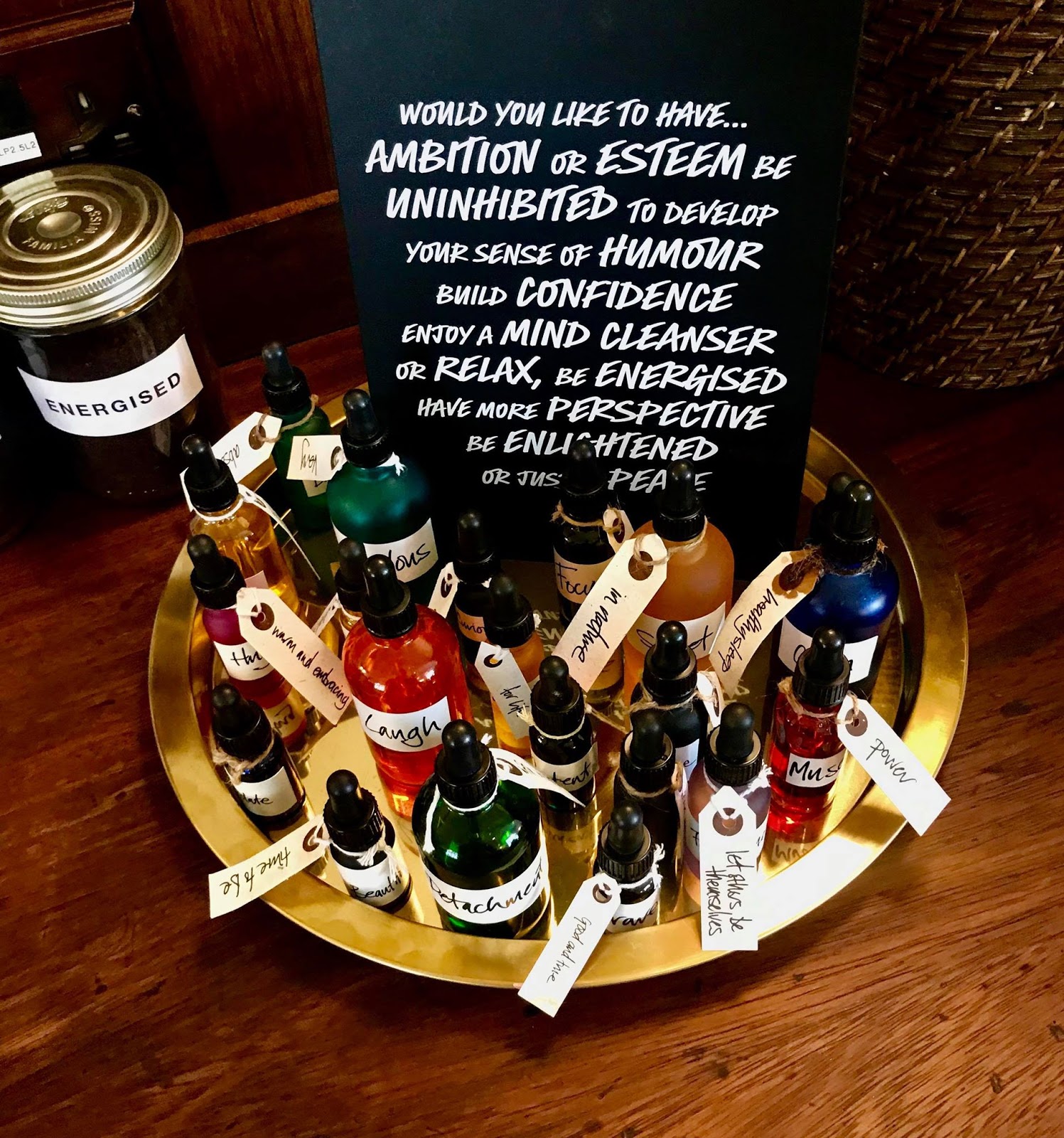 A large circular silver metal plate full of some short cylindrical black glass Vials on a dark wooden table, on a bright background.