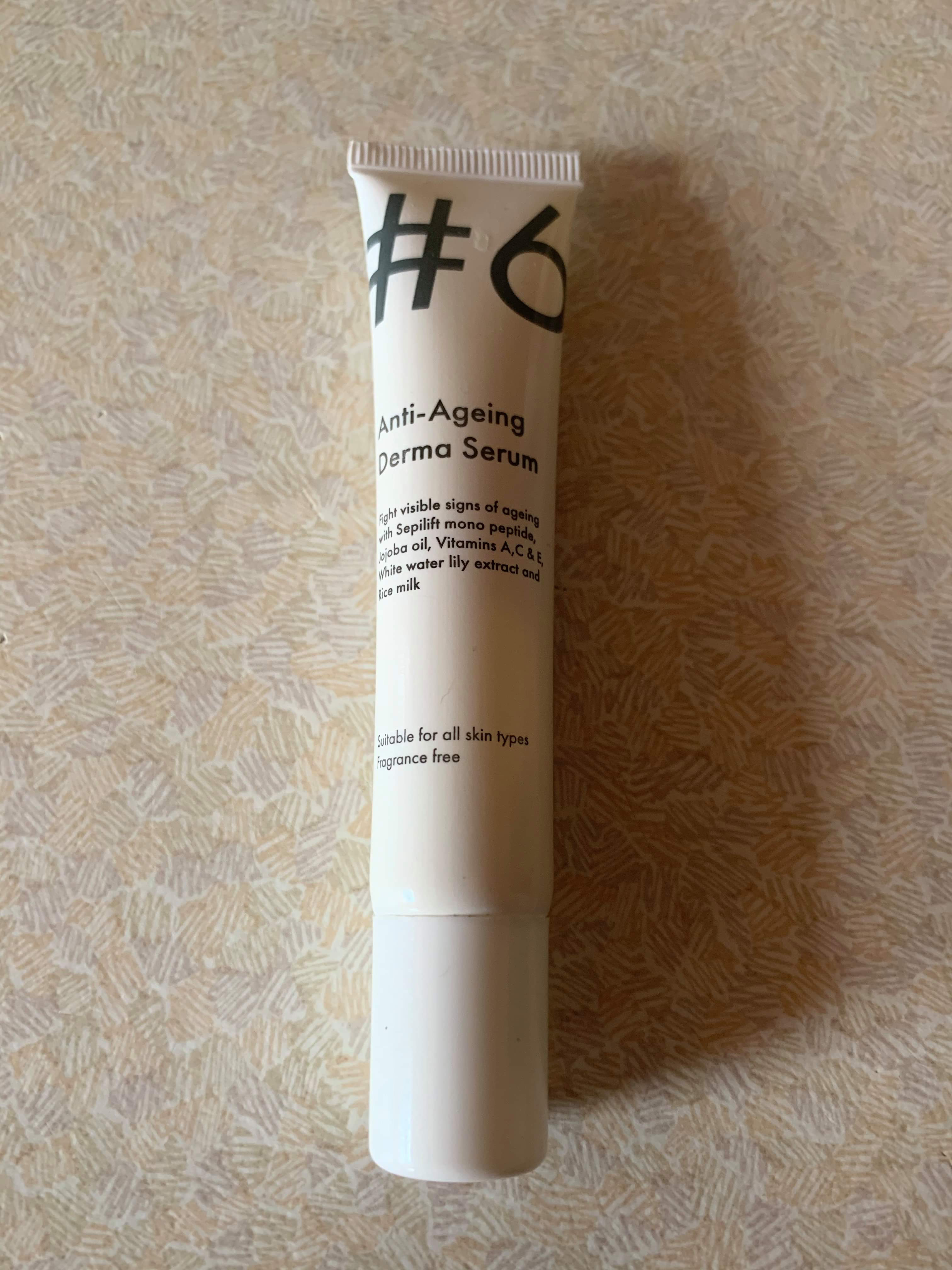 A short thin flat conical glossy white plastic tube that has Poundland #6 Anti-Ageing Derma Serum written in bold black writing on it, on a white background.