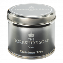 A short cylindrical silver tin with a bright pink label that has The Yorkshire Soap Company Christmas Tree Tin candle written in bold white writing on it, on a white background.