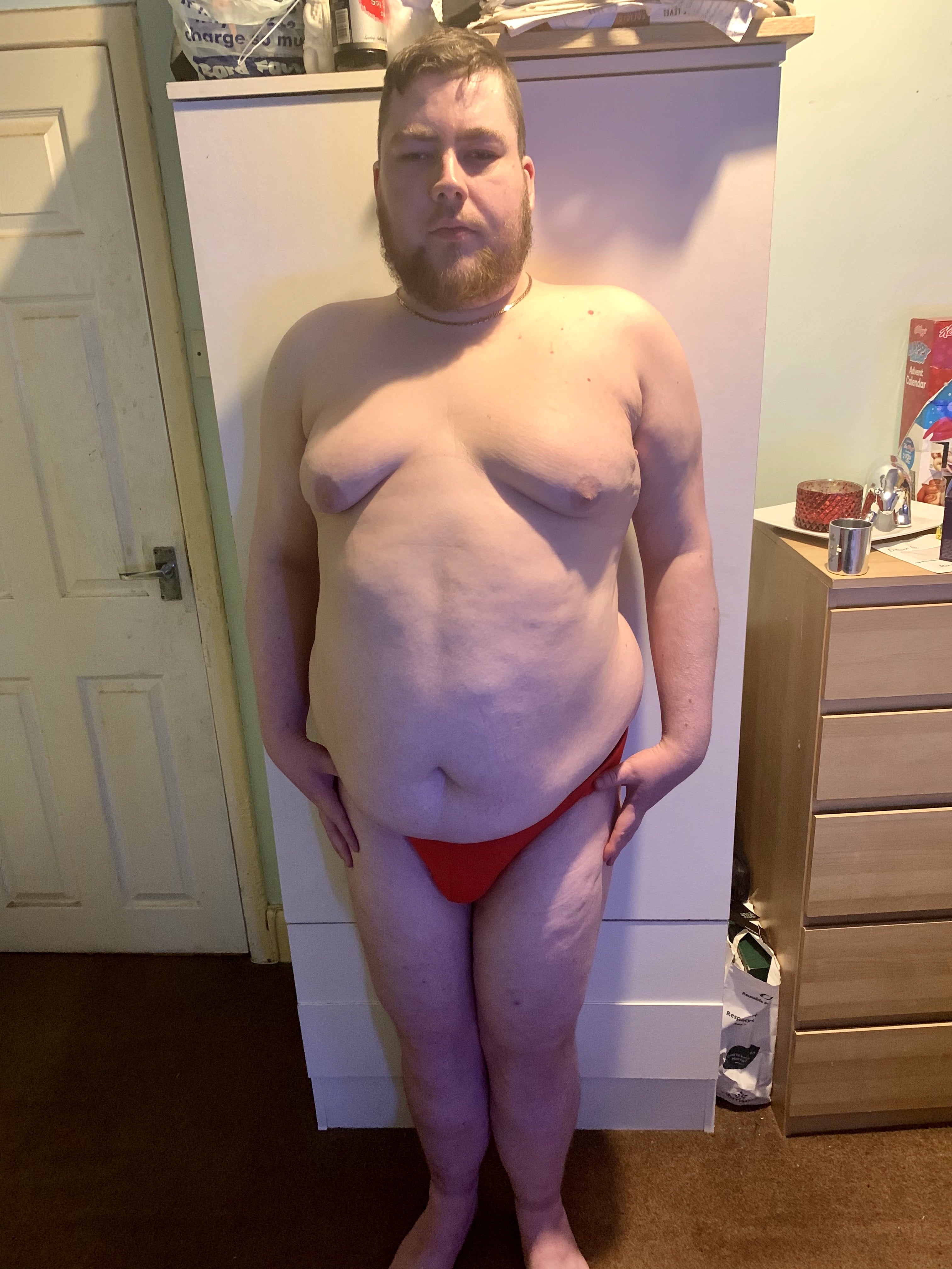 A bearded man wearing a pair of bright red briefs with a black waistband that has Bask Menswear written in bold white writing on it, on a white background.