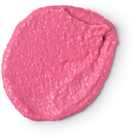 A small circular puddle of light pink body scrub that has some little pieces of Sea Salt in it, on a white background.