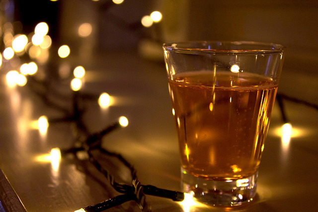 Sweet, Sugar, Candy Man! | Smith & Sinclair Leeds Pop Up Store Launch with The Alchemist Trinity Leeds A clear glass of a golden coloured drink, on a wooden background with unfocused fairy lights in the background.