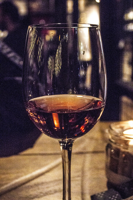 The Taste Of Good Wine | Veeno Leeds Wellington Place Selezione Wine Tasting A close up shot of some dark pink Rosé Wine in a tall clear wine glass on a wooden table, on a dark background.