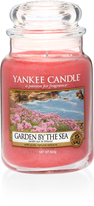 Oh I Do Like To Be Beside The Seaside | Yankee Candle Coastal Living Collection A tall glass jar full of bright Pink coloured wax, with a label that has a picture of some Flowers next to the Sea, and Yankee Candle and Garden by the Sea written in black writing on it, on a white background.