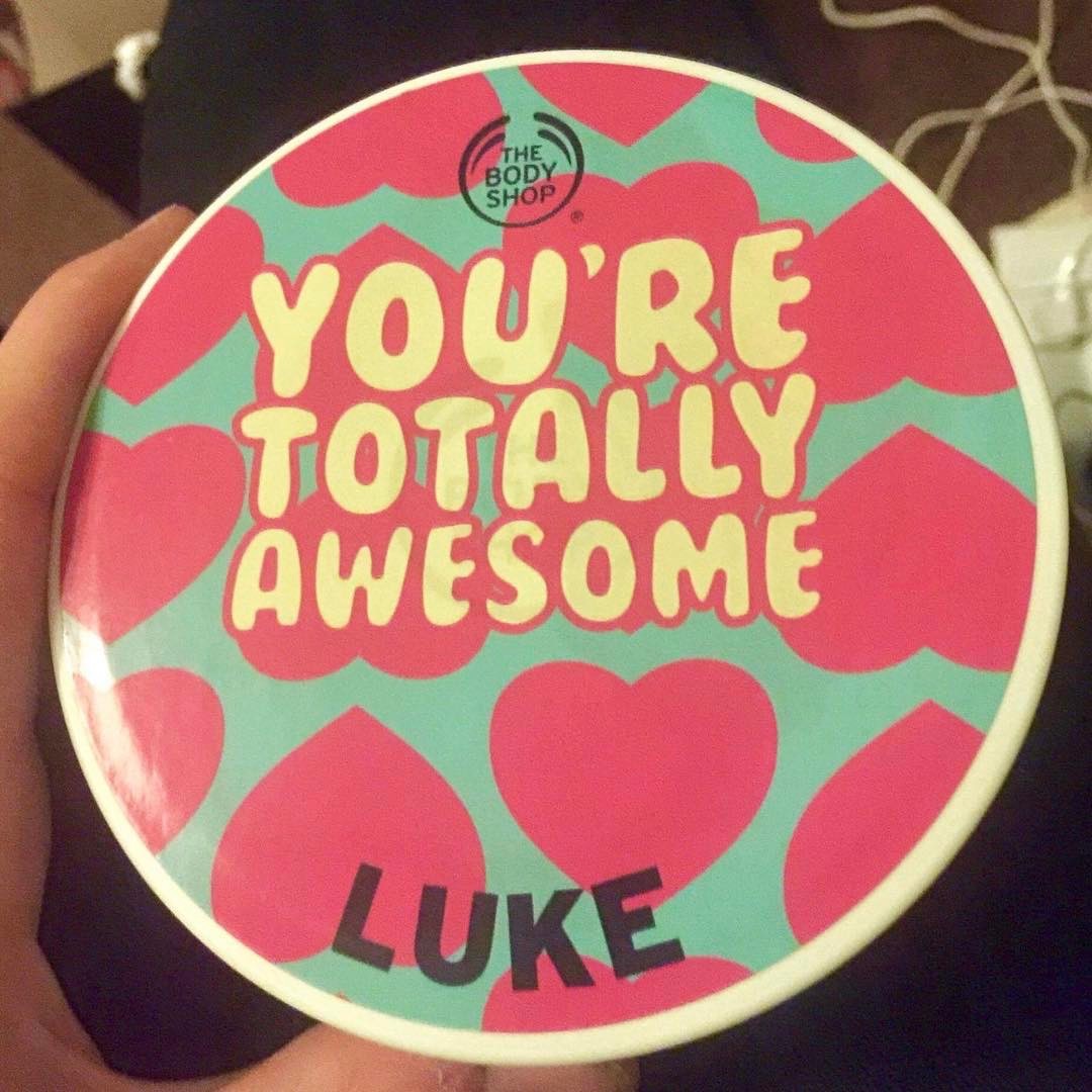 Mum! You're Totally Awesome | The Body Shop Leeds Briggate Mother's Day Event A white circular tub with a lid that has a green sticker on it with You're totally awesome written in white bubble writing and Luke written in black bubble writing surrounded by some hearts, on a dark background.