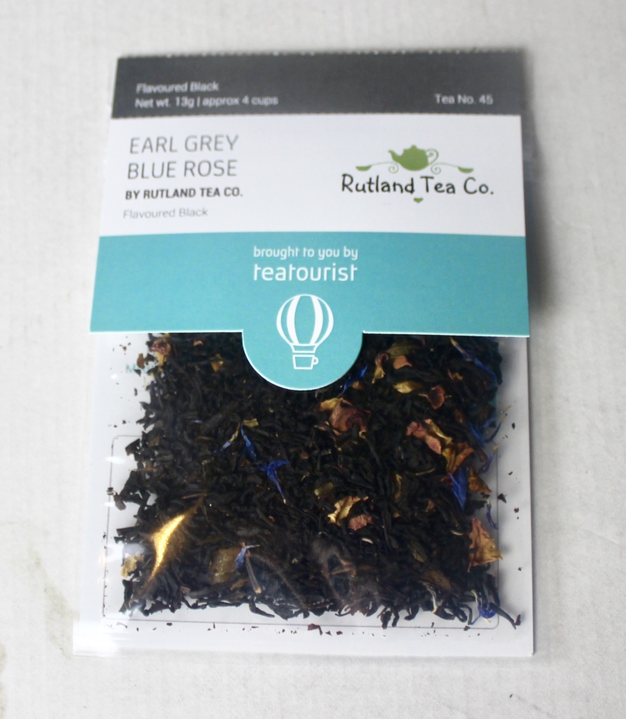 Rose Always Works A Charm | Aldi Lacura Vitamin C Hot Cloth Cleanser, Rose Tonic & Rose Facial Oil A square clear plastic bag containing some dark brown tea leaves with a cardboard label that has Earl Grey Blue Rose written in medium blue writing and Rutland Tea Company written in smaller brown writing on it, on a white background.