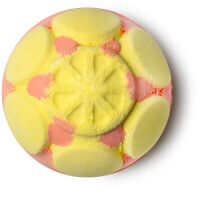 A bright green coloured circular bath bomb with some yellow coloured hexagonal detailing and a sun engraved on the top of it, on a white background.