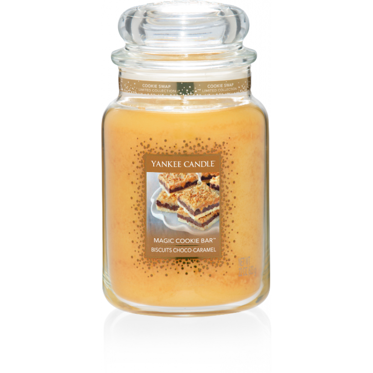 That's The Way The Cookie Crumbles | Yankee Candle Cookie Swap Collection A tall glass jar full of some light Gold coloured wax with a label that has yankee candle written in white writing, Magic Cookie Bar written in black writing, and a picture of a Cookie Bar with it's filling exposed on it, on a white background.