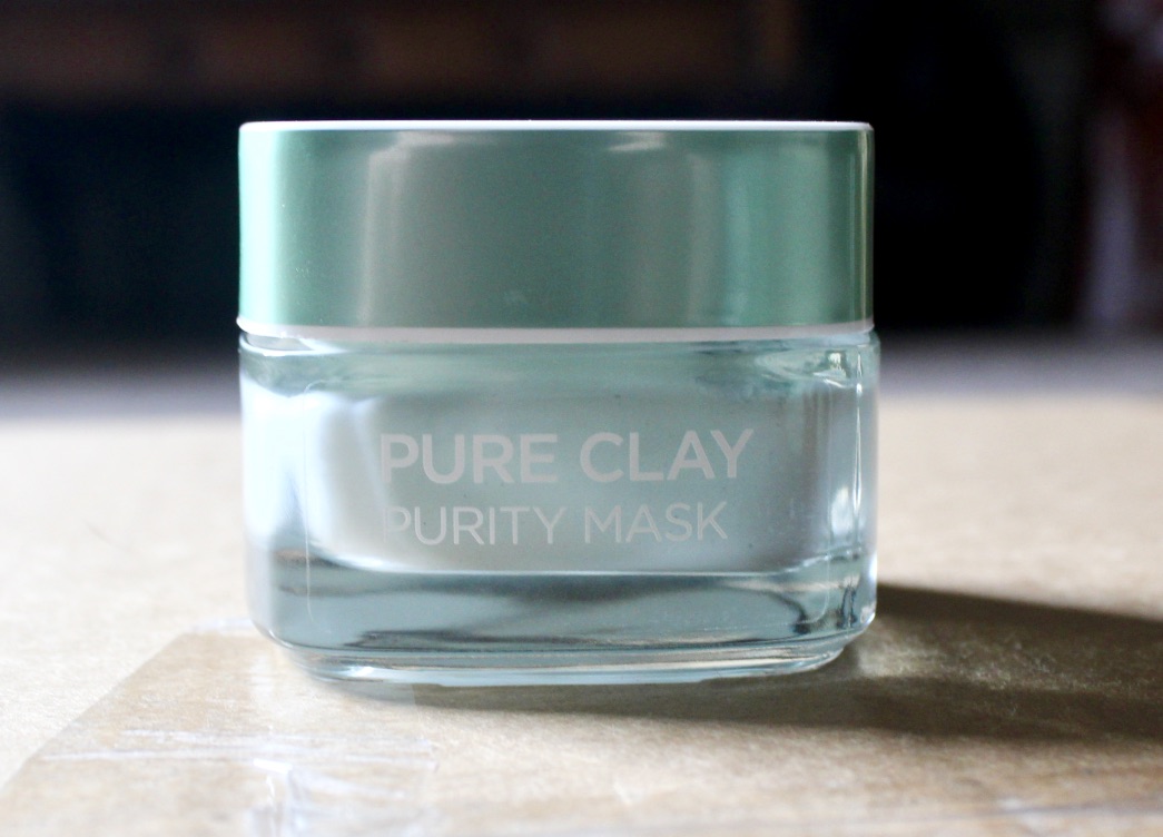 Review | L'oreal Men Expert Pure Power Red Volcano Wash A square glass tub full of some bright grey coloured face mask with a bright silver coloured square lid on a wooden table, on a bright background.