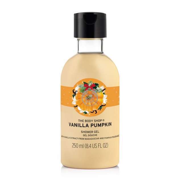 A tall clear plastic bottle filled with some thick white shower gel, a black plastic lid, and a label that has Vanilla Pumpkin written in large black writing and The Body Shop Shower Gel written in smaller black writing on it, on a white background.