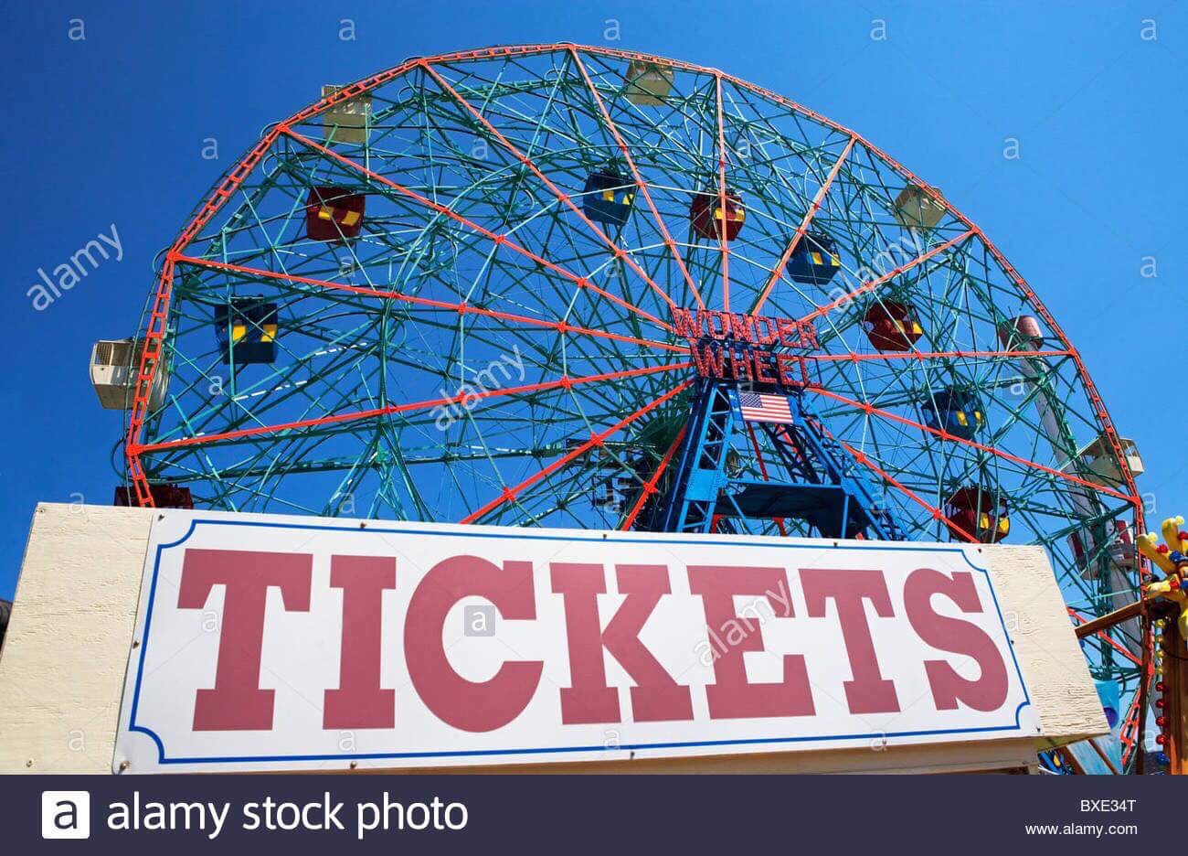 Five Things I Hate About Living Opposite A Fairground A bright Red Metal Ferris Wheel behind a white rectangular banner that has Tickets written in bold Red writing on it, on a white background.