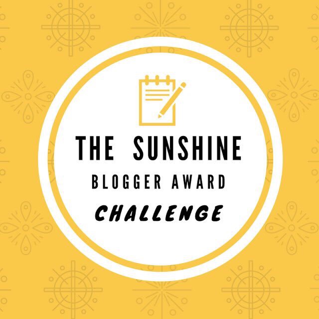 A white circle with a yellow border that has The Sunshine Blogger Award’s Challenge written in bold black writing on it, on a yellow background.