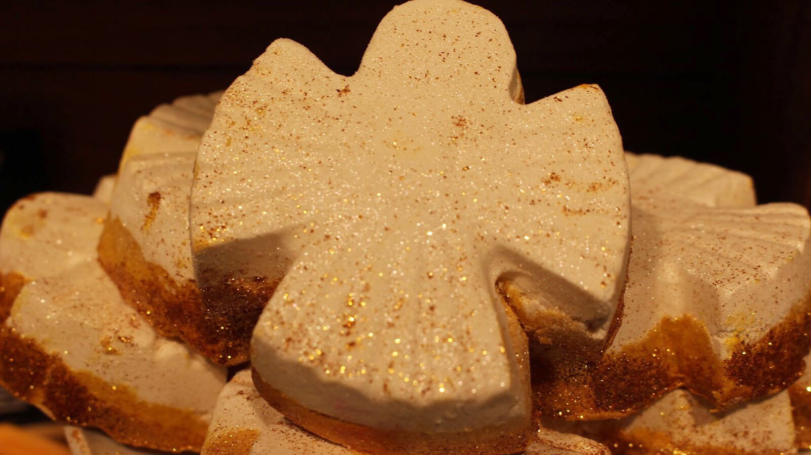 Marvellous Marzipan Magic | Lush Snowcake Soap and Snow Angel Bath Melt A brown angel shaped bath melt that has some silver lustre on top of it, on a white background.