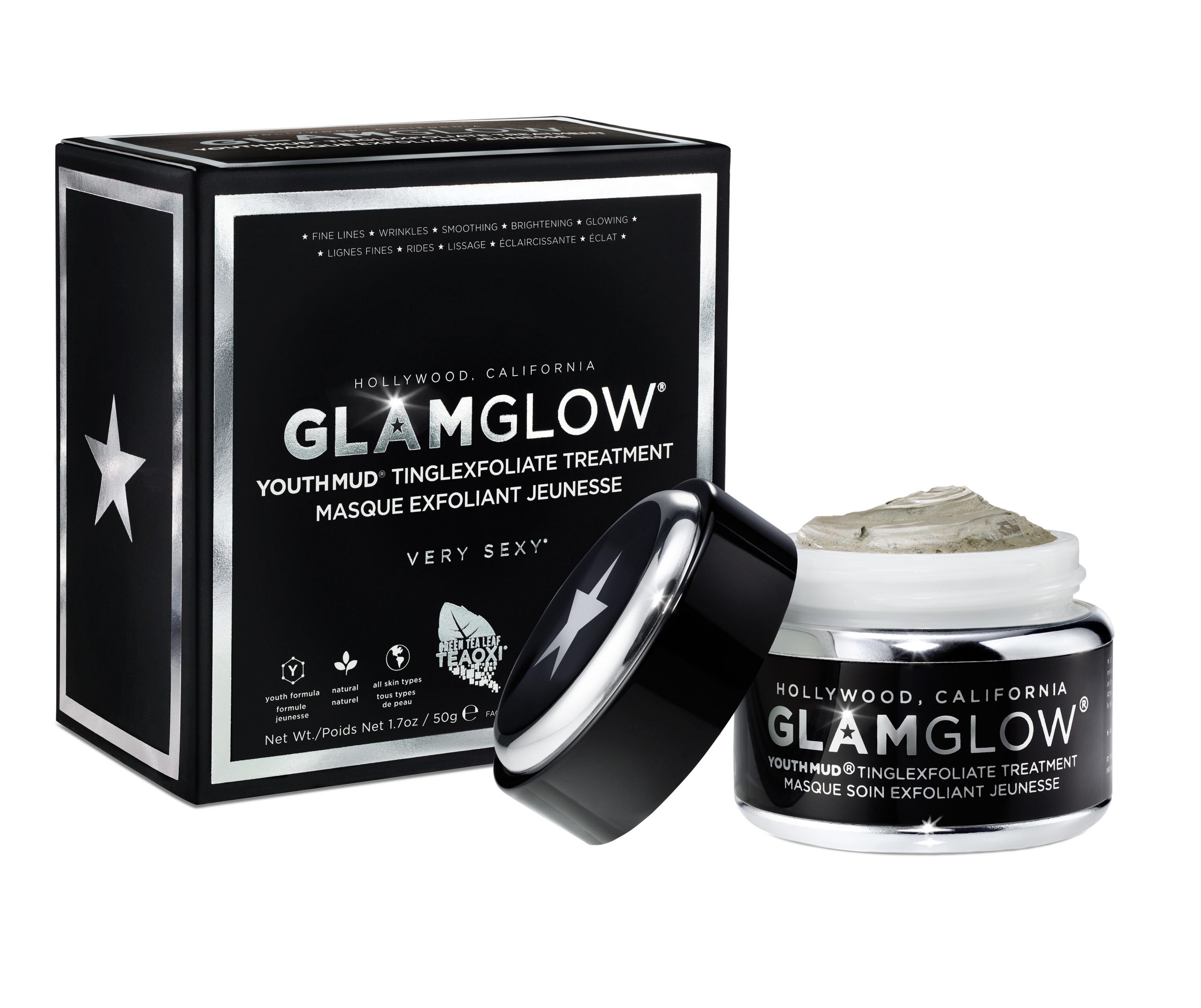 The Tingle Of Youth | GlamGlow YouthMud® Tinglexfoliate Treatment A short cylindrical black glass jar with a black lid that has GlamGlow YouthMud® Tinglexfoliate Treatment written in bold silver writing and a picture of a silver star on it next to a small rectangular black and silver box that has GlamGlow YouthMud® Tinglexfoliate Treatment written in bold silver writing and a picture of a silver star on it, on a white background.