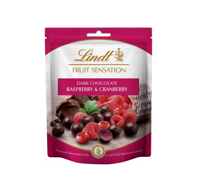 A rectangular white and purple plastic pouch that has Lindt Fruit Sensation written in cursive gold writing, Raspberry & Cranberry written in bold white writing, and a picture of some raspberries and some cranberries on it, on a white background.