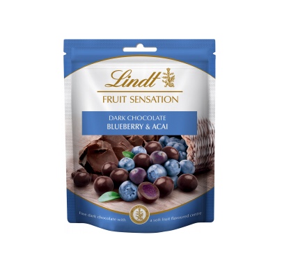 The Sensational Taste Of Fruit | Lindt Fruit Sensation Range A rectangular blue and white plastic pouch that has Lindt Fruit Sensation written in cursive gold writing, Blueberry & Acai written in bold white writing, and a picture of some blueberries and some Acai Berries on it, on a white background.