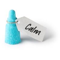 I'm In One Hell Of A Mood | Lush #LushMood Range A sky blue miniature bottle shaped bath bomb with a paper label that has Calm written in bold black writing on it, on a white background.