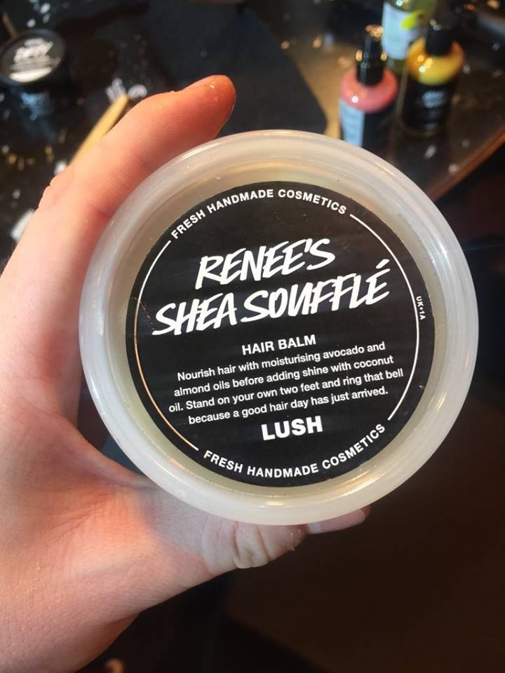A cylindrical clear plastic tub with a black label that has Renee's Hair Soufflé written in bold white writing on it, on a white background.
