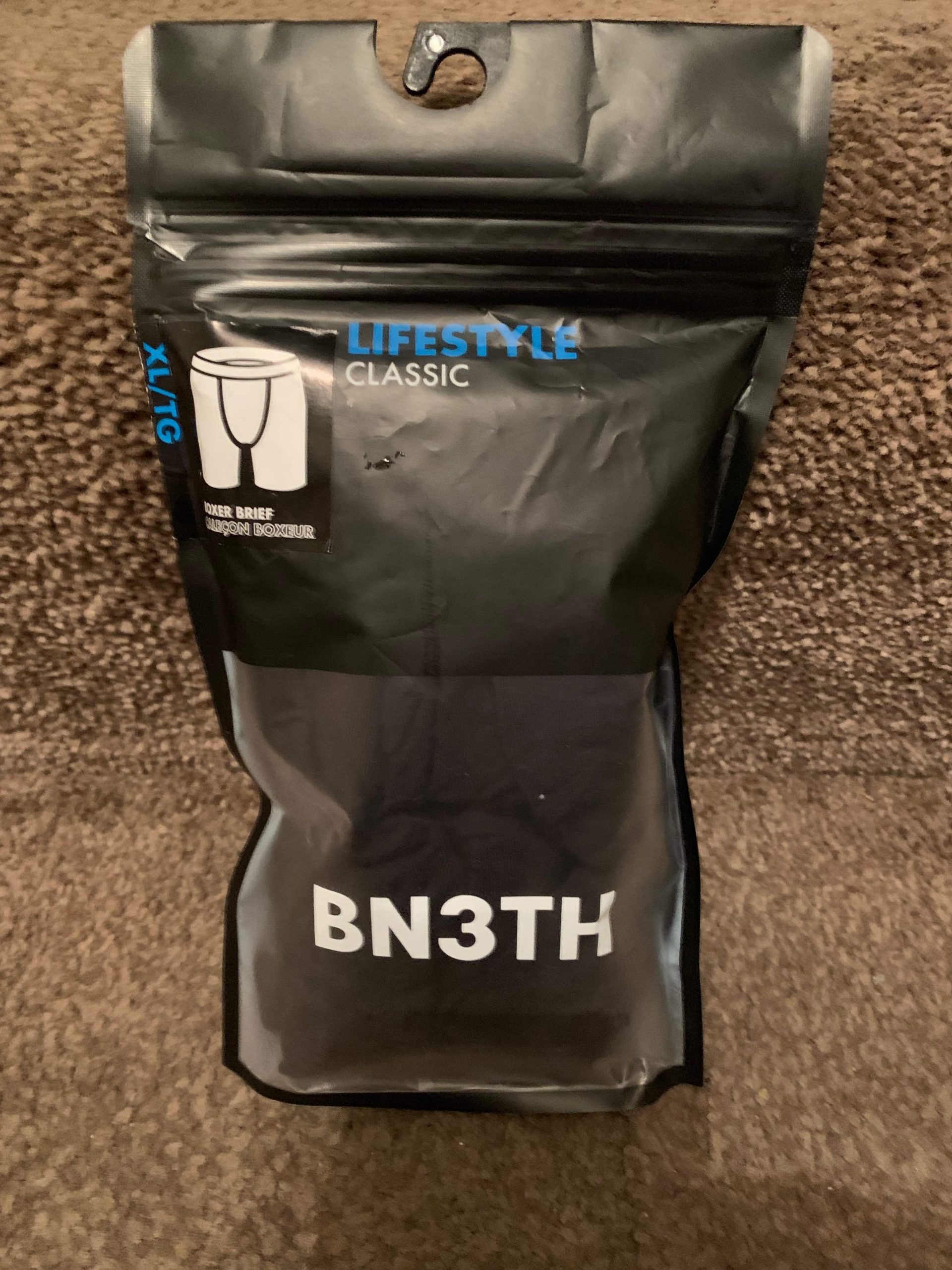 What's Really Beneath My Clothes | Bn3th Classic Black/Red Boxer Briefs A tall rectangular clear plastic pouch full of some black and red material that has Bn3th Classic Black/Red Boxer Briefs written in bold black writing on it, on a white background.