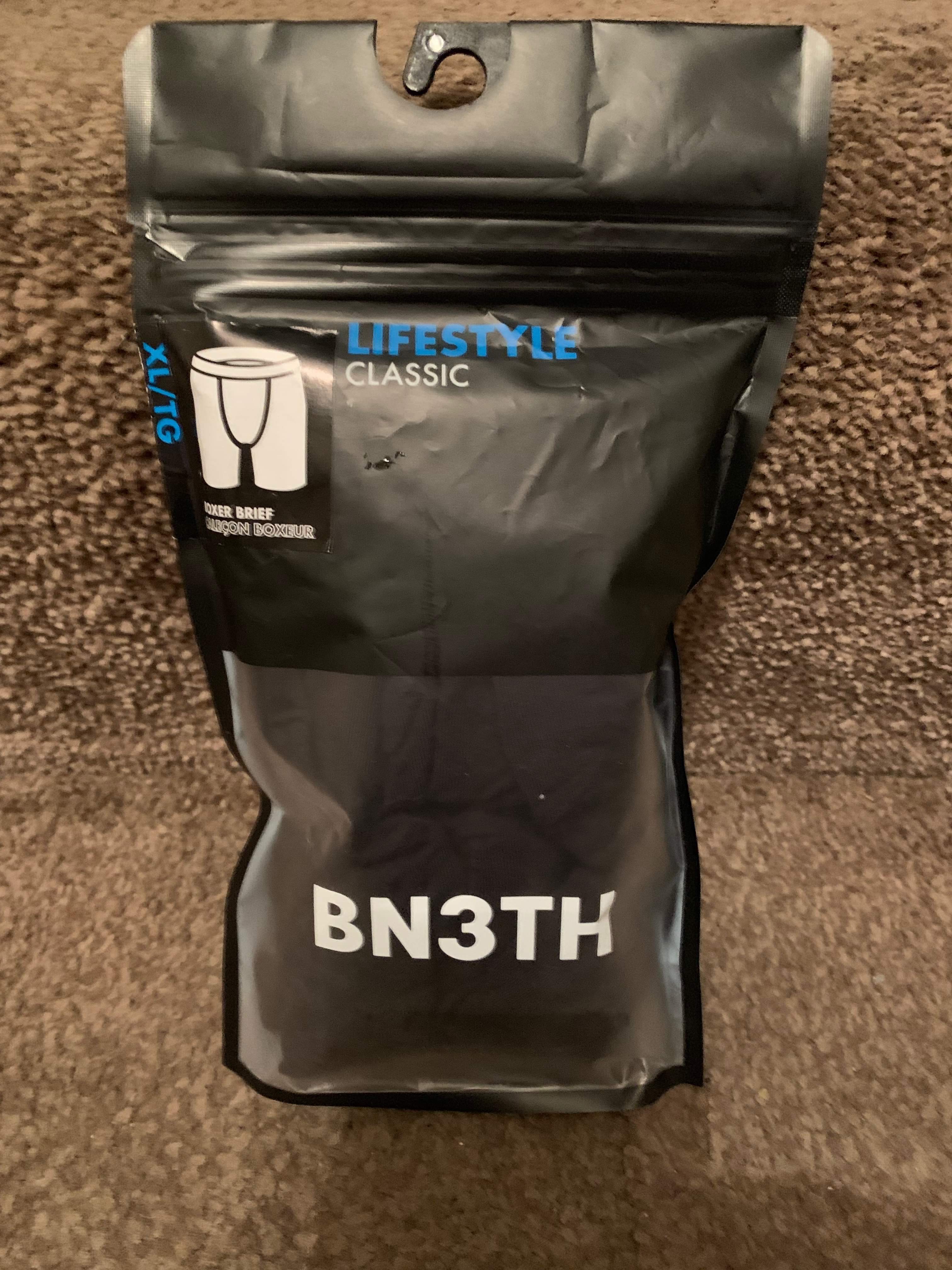 What's Really Beneath My Clothes | Bn3th Classic Black/Red Boxer Briefs A tall rectangular clear plastic pouch full of some black and red material that has Bn3th Classic Black/Red Boxer Briefs written in bold black writing on it, on a white background.