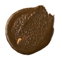 Would You Like Smooth Skin With Your Morning Coffee? | Lush Cup O' Coffee Face & Body Mask A large circular puddle of dark brown liquid with some pieces of grit in it, on a white background.
