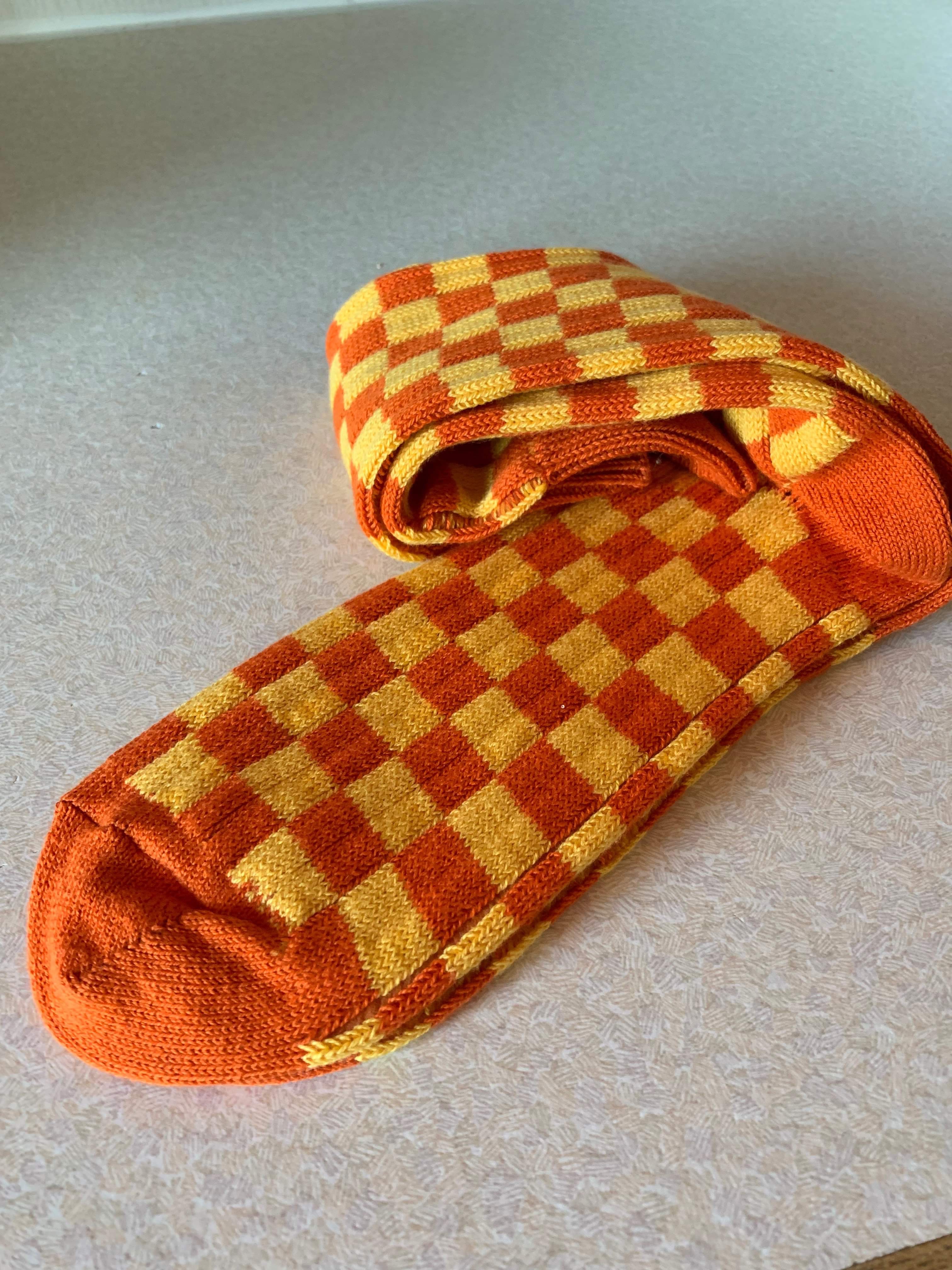 Welcome To The Club | Sock Club Sock Subscription | Gifted A pair of large orange and yellow checked socks, on a white background.