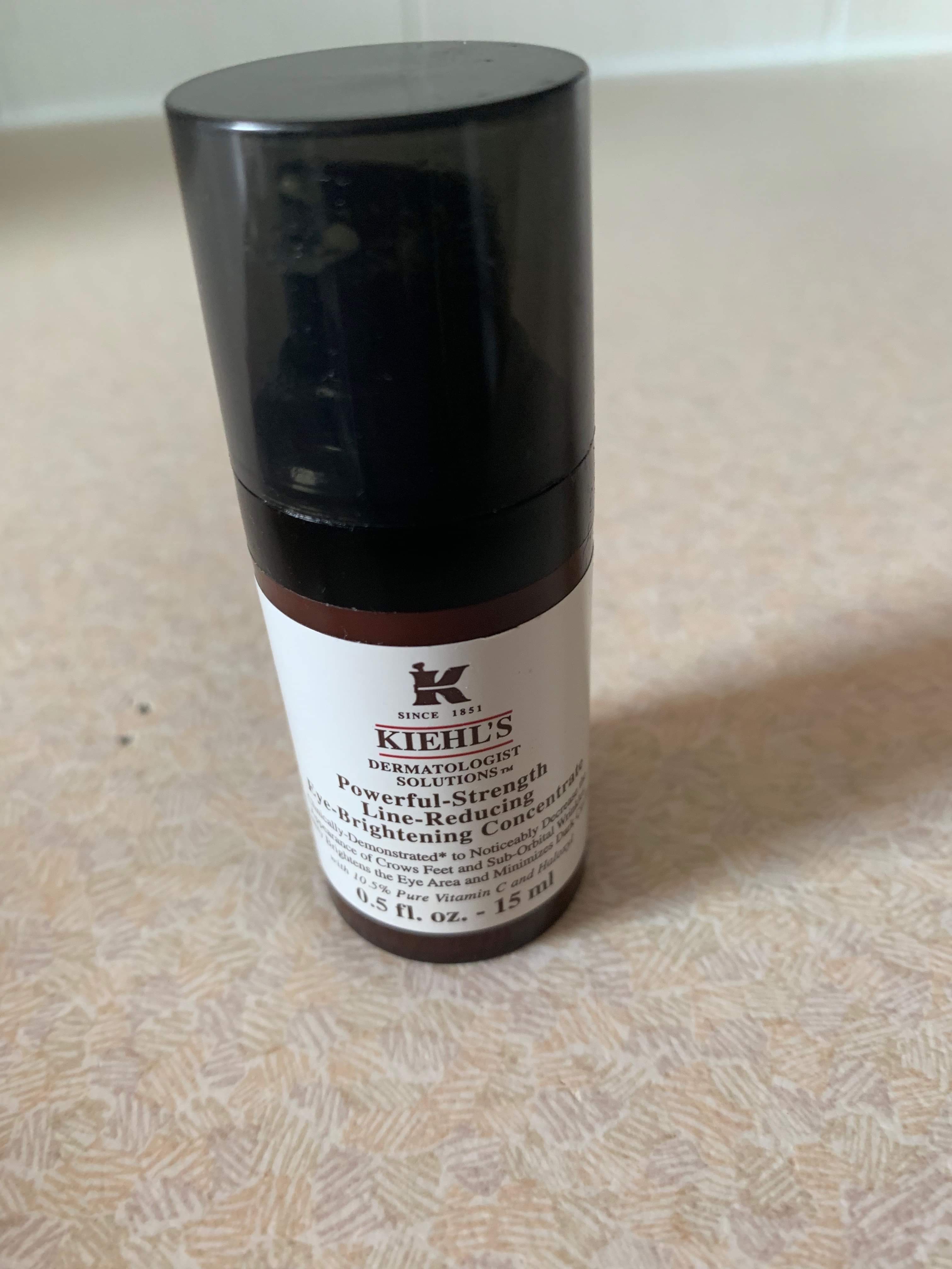 Concentrating Can Actually Reduce Lines | Kiehl’s Powerful-Strength Line-Reducing Eye-Brightening Concentrate | Gifted A short cylindrical black plastic bottle with a white label that has Kiehls Powerful-Strength Line-Reducing Eye-Brightening Concentrate written in bold black writing on it, on a white background.