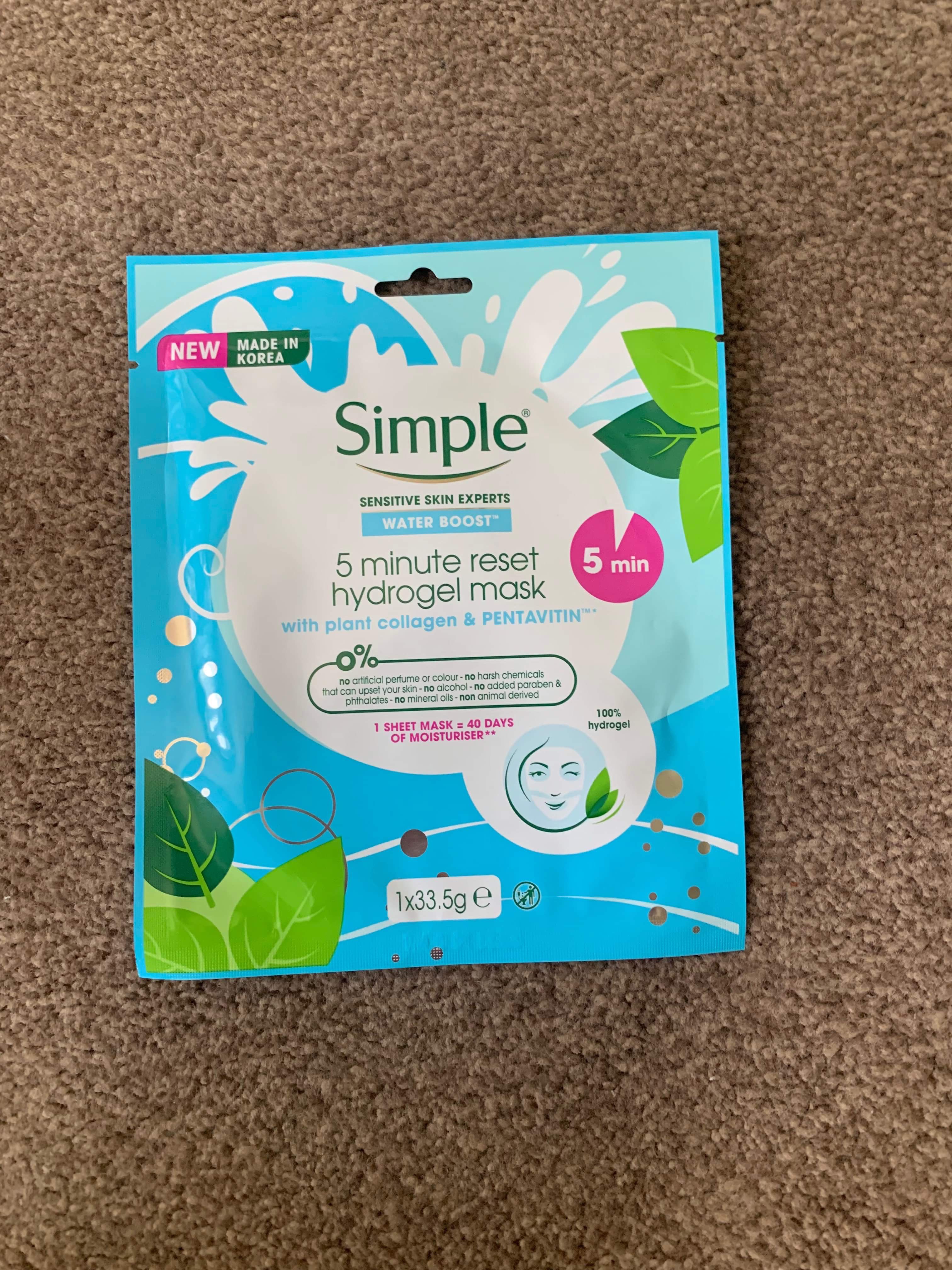 A Simple Boost Of Hydration | Simple Water Boost 5 Minute Reset Hydrogel Sheet Mask A tall rectangular blue and white plastic pouch that has Simple Water Boost 5 Minute Reset Hydrogel Sheet Mask written in bold black writing and some pictures of some green leaves on it, on a white background.