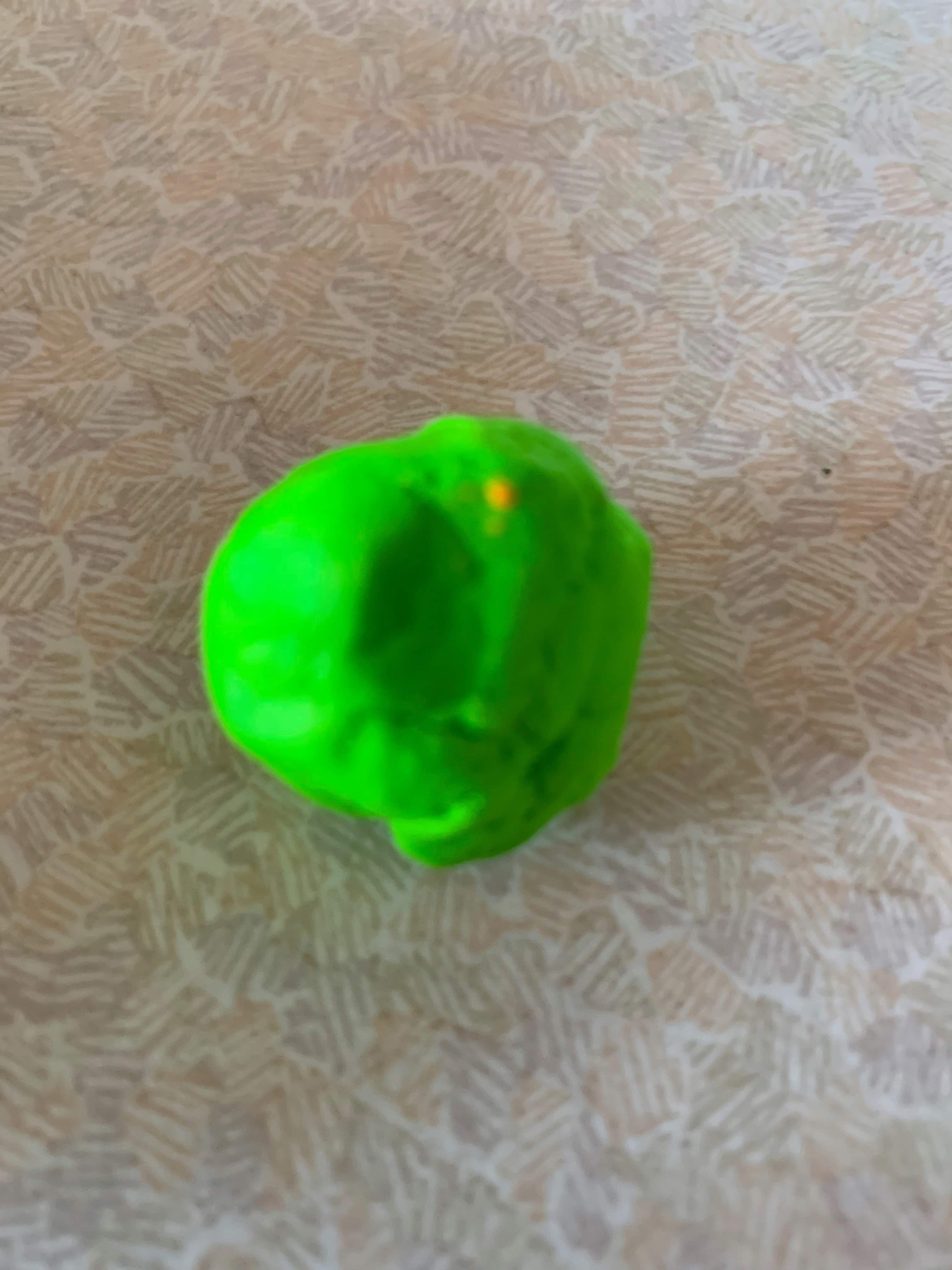 A large circular blob of bright green plasticine, on a white background.