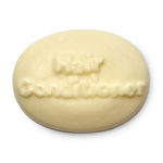 Making My Hair Feel As Big As The Sea | Lush Big Shampoo & Big Solid Conditioner A large oval block of pale blue solid conditioner that has conditioner engraved on the top of it, on a white background.