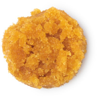 A small circular puddle of dark orange lip scrub, on a white background.