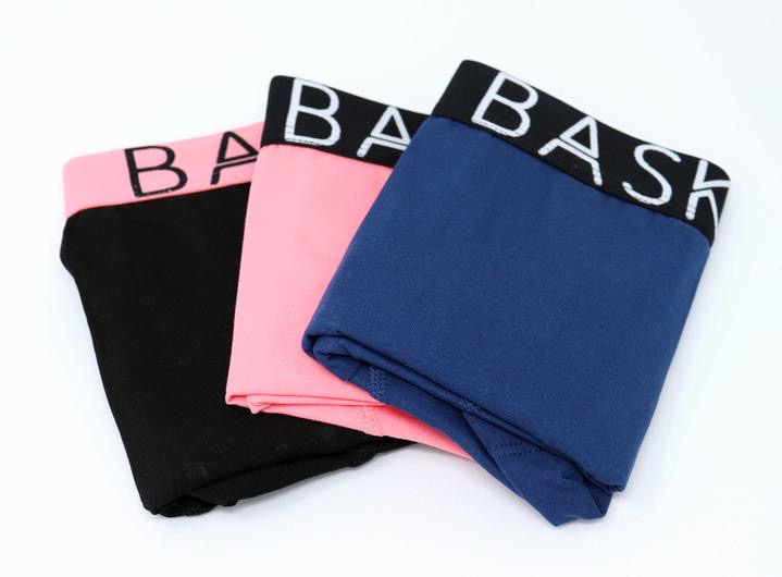 A pair of black boxers with a black waistband that has Bask Menswear written in bold white writing on it next to a pair of Navy Boxers with a black waistband that has Bask Menswear written in bold white writing on it and a pair of coral boxers with a black waistband that has Bask Menswear written in bold white writing on it, on a white background.